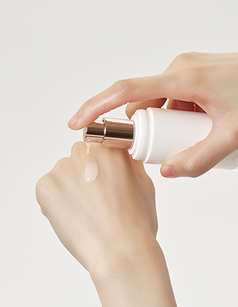 Hand applying a white cream to another hand on a light gray background